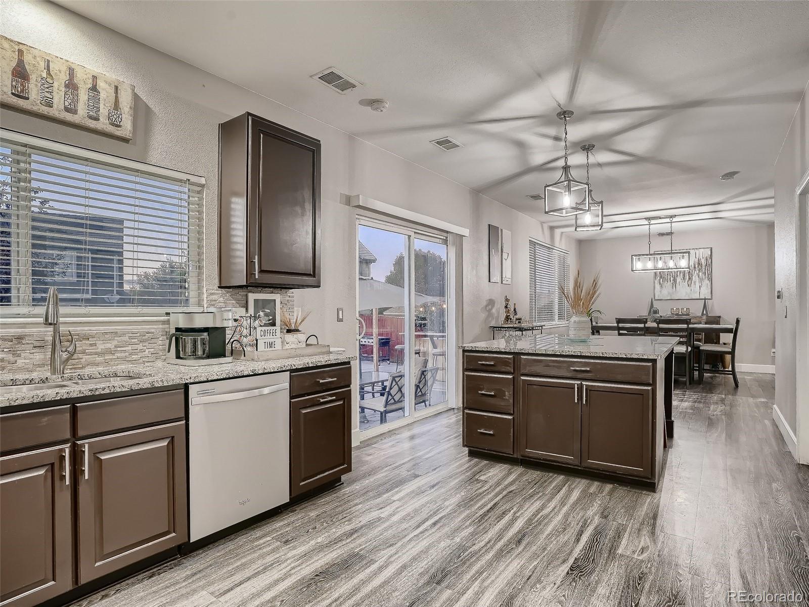 10047 Crystal Circle Commerce City, CO 80022 - Photo 12 of 28 a large kitchen with stainless steel appliances and wooden floor