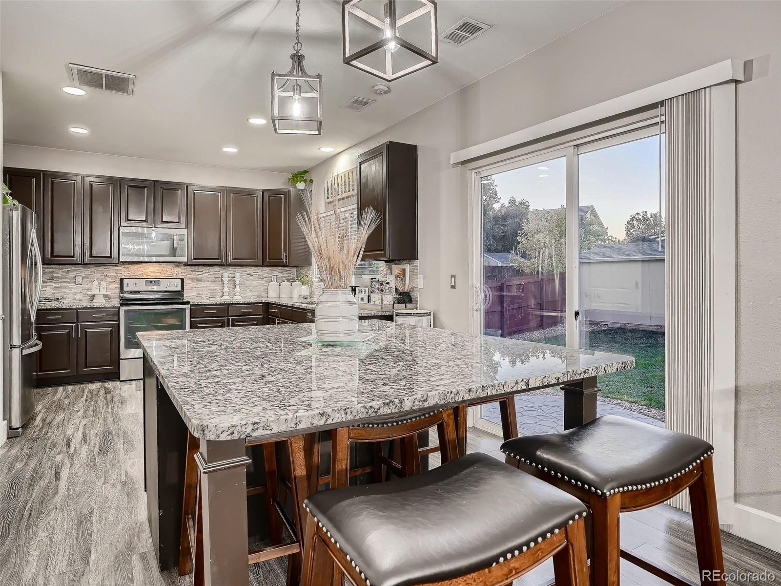 10047 Crystal Circle Commerce City, CO 80022 - Photo 14 of 28 a kitchen with a table chairs and wooden floor