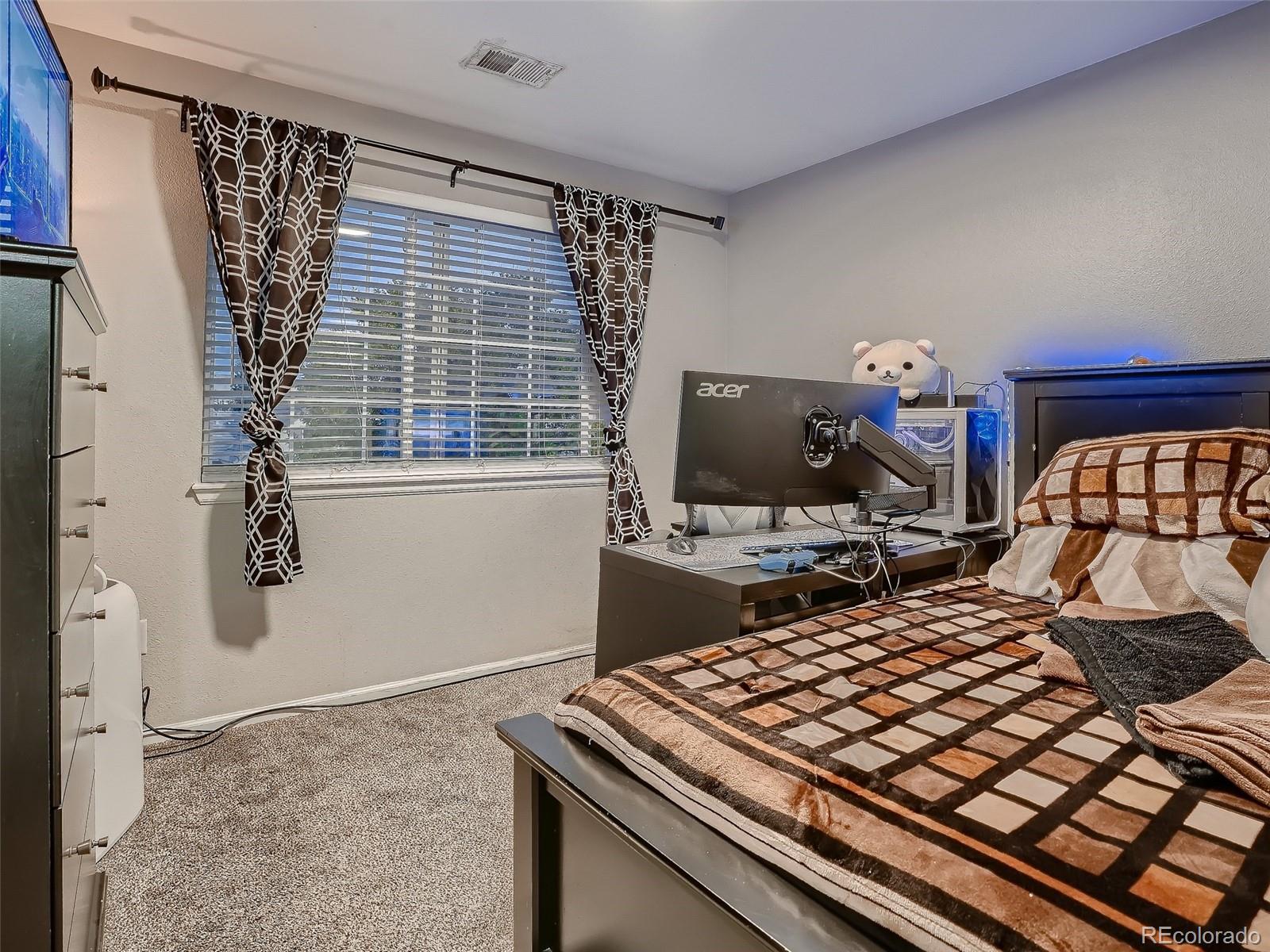 10047 Crystal Circle Commerce City, CO 80022 - Photo 19 of 28 a bedroom with a bed and a flat tv screen