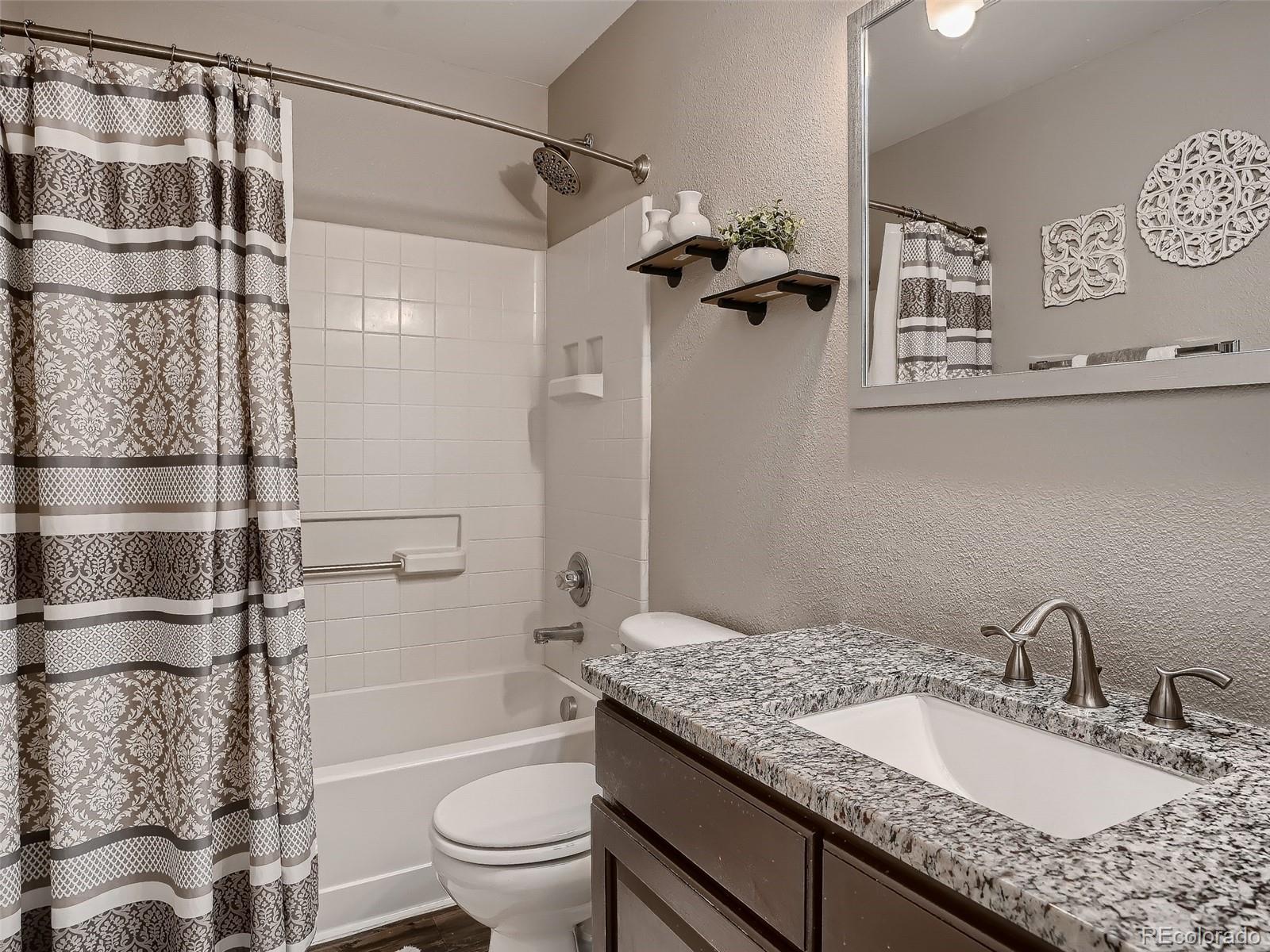 10047 Crystal Circle Commerce City, CO 80022 - Photo 21 of 28 a bathroom with a granite countertop sink a toilet and shower