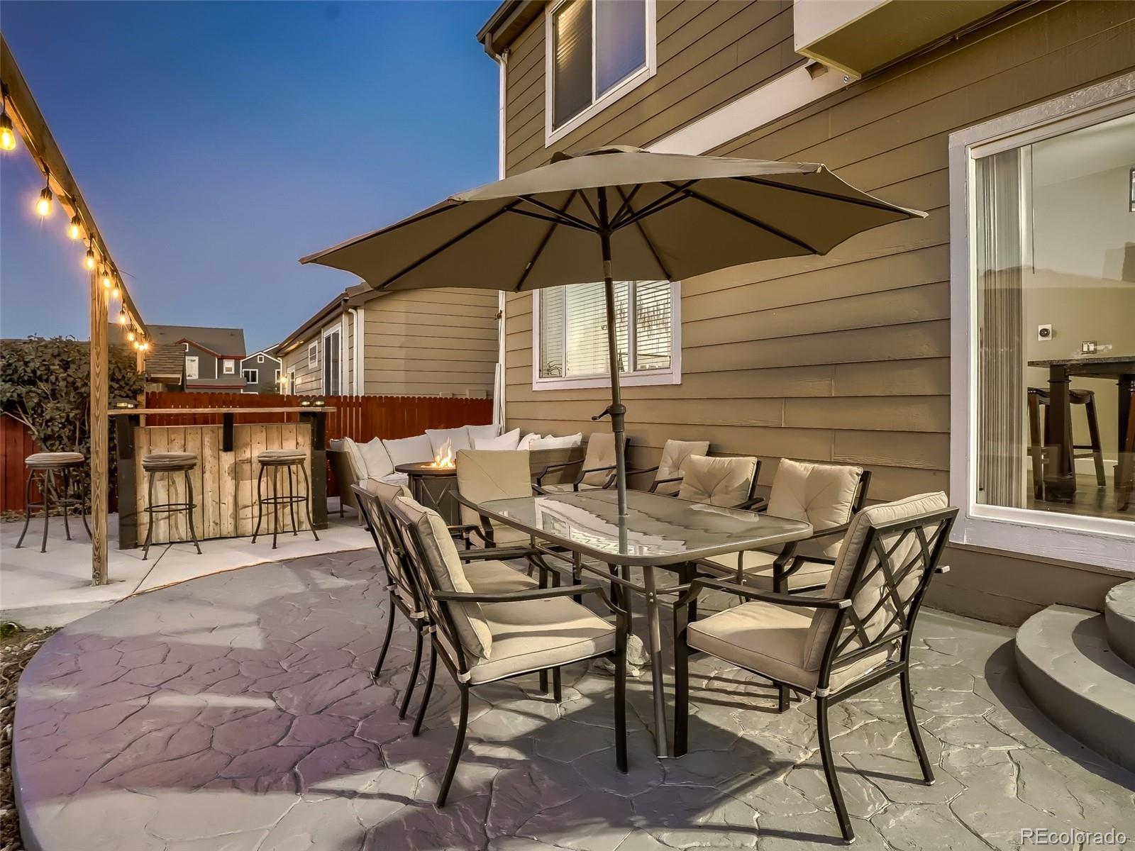 10047 Crystal Circle Commerce City, CO 80022 - Photo 24 of 28 a patio with a table and chairs under an umbrella