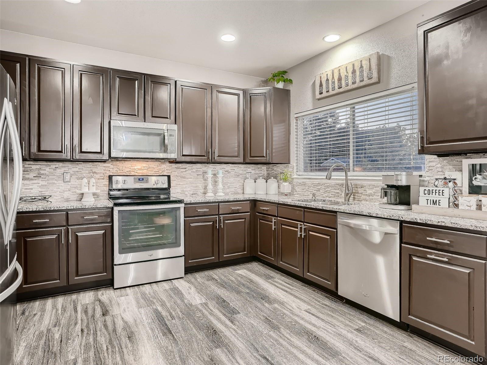 10047 Crystal Circle Commerce City, CO 80022 - Photo 10 of 28 a kitchen with granite countertop cabinets stainless steel appliances and a sink