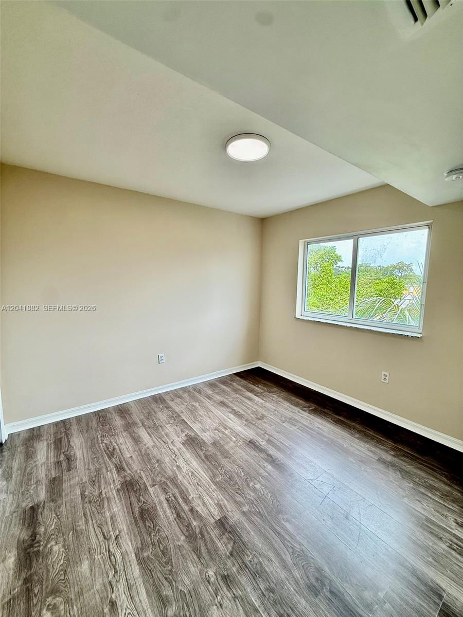 2475 Northwest 16th St Road, Unit 418 Miami, FL 33125 - Photo 11 of 27 an empty room with wooden floor and windows