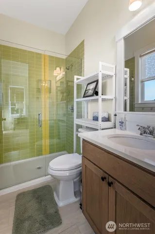 a bathroom with a granite countertop sink a toilet a mirror and shower