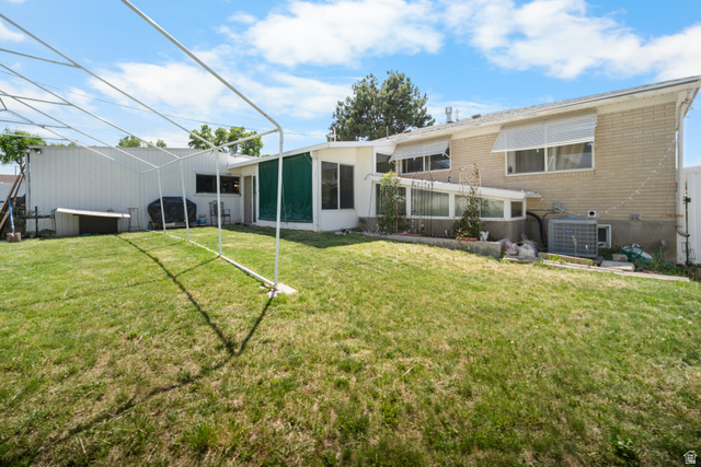 3233 Jean Street Magna, UT 84044 - Photo 3 of 33 Expansive backyard featuring a large lawn, brick exterior, multiple windows with awnings, and a sunroom with green screening