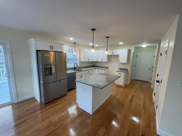 a kitchen with stainless steel appliances granite countertop a refrigerator a sink a stove and a wooden floors