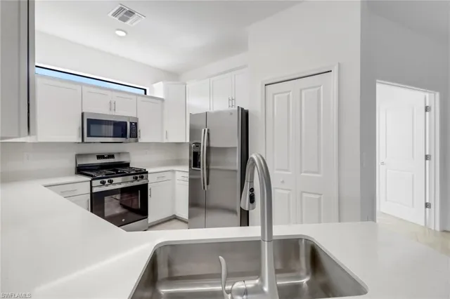 a kitchen with stainless steel appliances granite countertop a refrigerator a stove and a sink with wooden floor