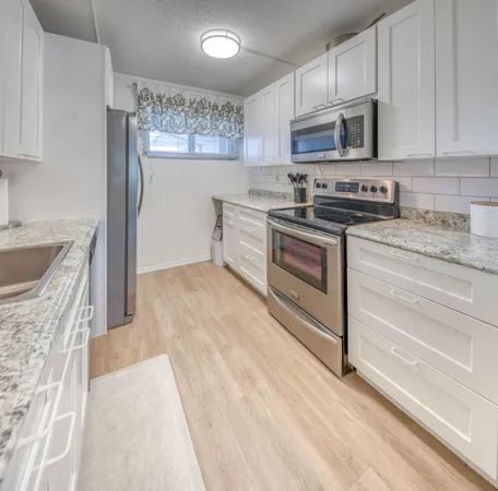 a kitchen with stainless steel appliances granite countertop a stove a sink and a refrigerator