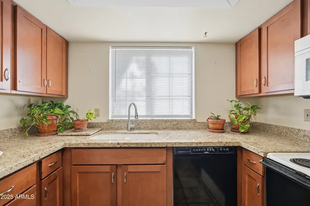 a kitchen with granite countertop a sink window and cabinets