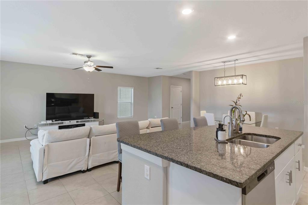9440 Lemon Drop Loop Sun City Center, FL 33573 - Photo 19 of 55 a kitchen with granite countertop a sink and a flat screen tv