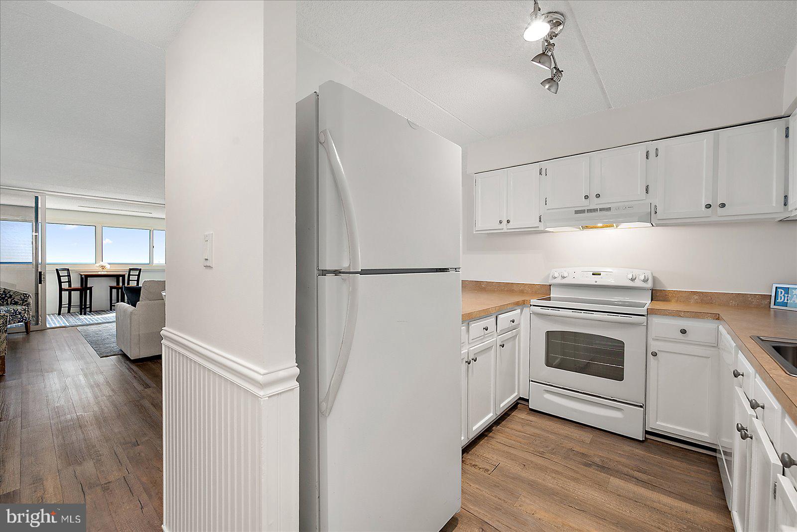 10300 Coastal Highway, Unit 1808 Ocean City, MD 21842 - Photo 12 of 47 a kitchen with cabinets stainless steel appliances and wooden floor