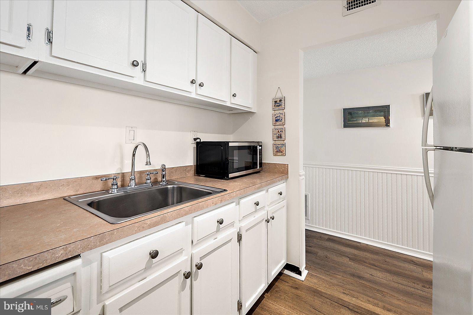 10300 Coastal Highway, Unit 1808 Ocean City, MD 21842 - Photo 15 of 47 a kitchen with white cabinets and a sink