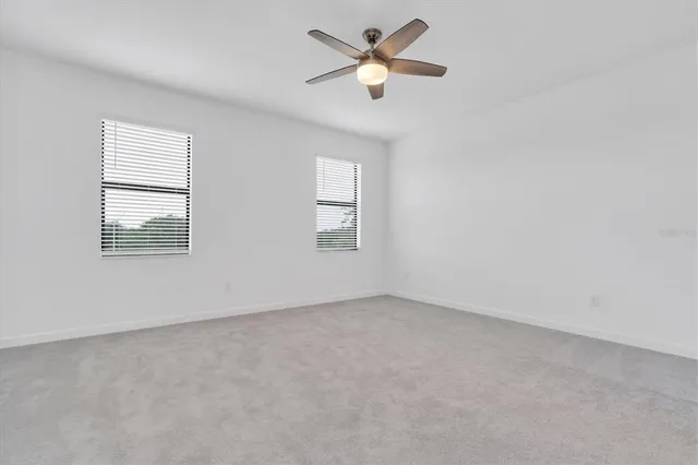 an empty room with chandelier fan and windows