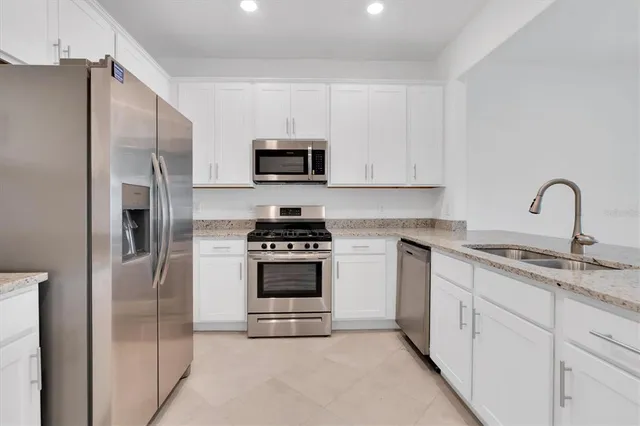 a kitchen with stainless steel appliances white cabinets a sink stove and refrigerator