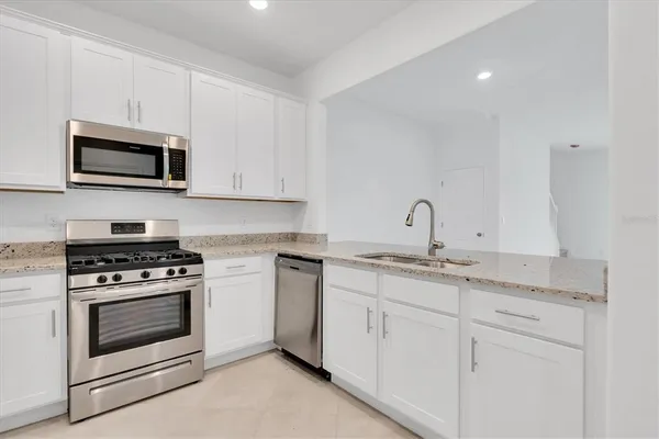 a kitchen with stainless steel appliances granite countertop a sink a stove and a refrigerator