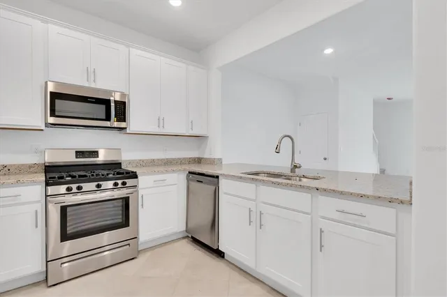 a kitchen with stainless steel appliances granite countertop a sink a stove and a refrigerator