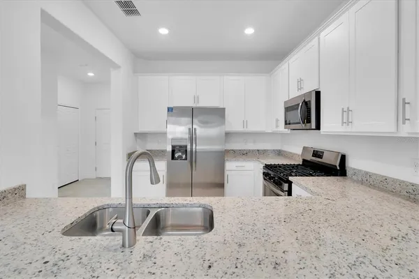 a large white kitchen with a sink and dishwasher a refrigerator with white cabinets