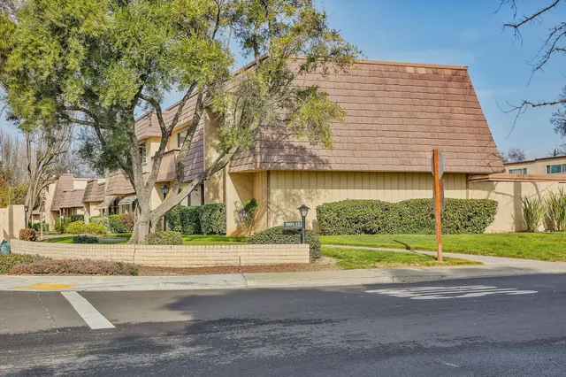 a view of a house with a garden and large trees