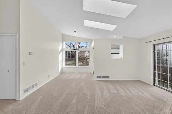 an empty room with windows and chandelier fan