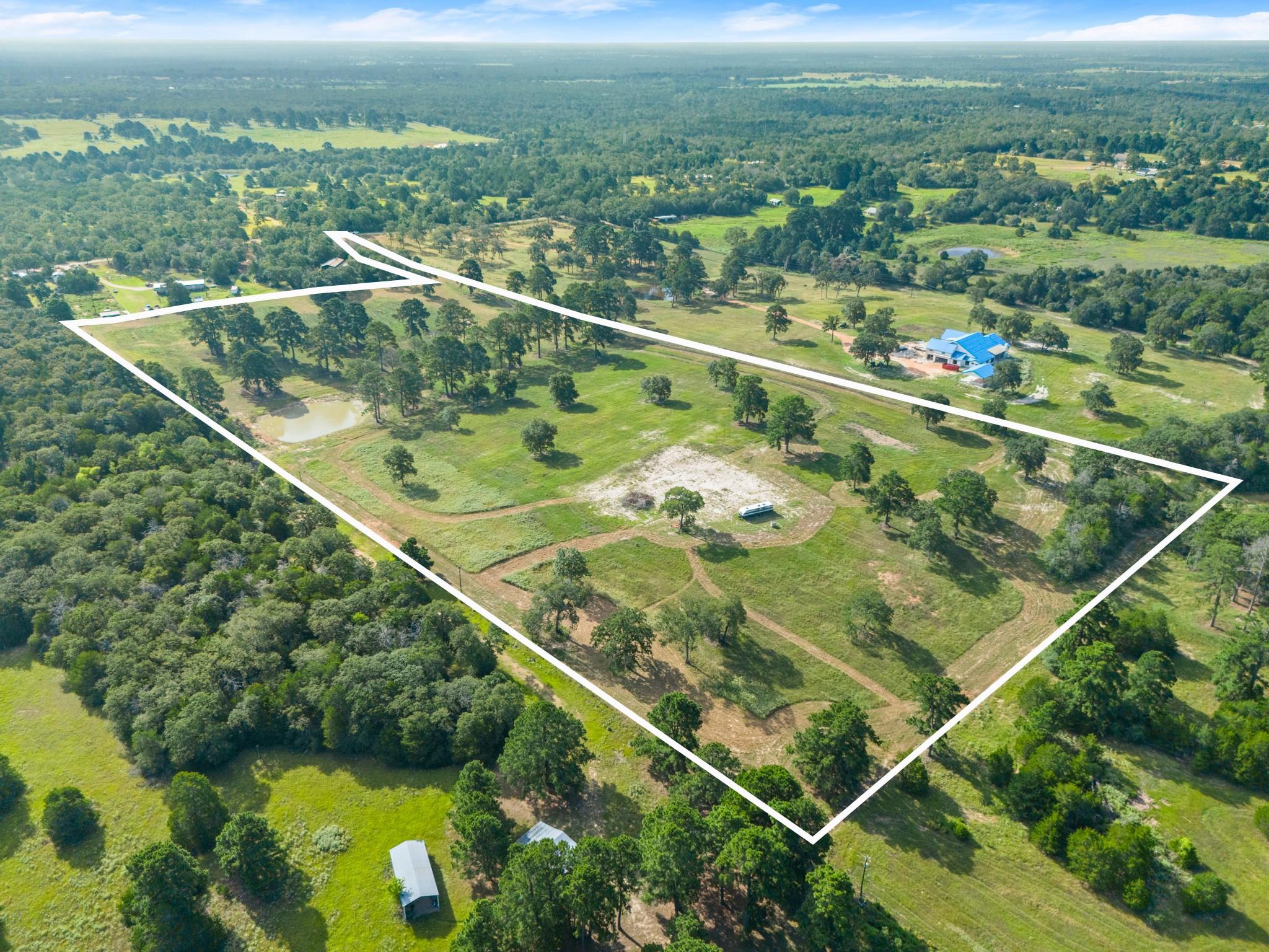 170 Split Oak Road Smithville, TX 78957 - Photo 2 of 31 An expansive rural property, marked by mature trees and verdant fields, presents an idyllic setting for a private estate.