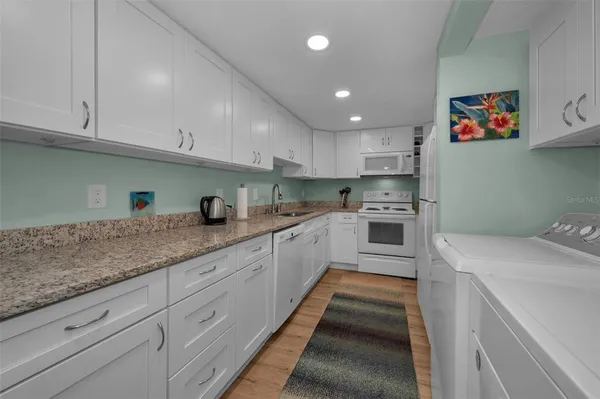 a kitchen with white cabinets sink and white appliances