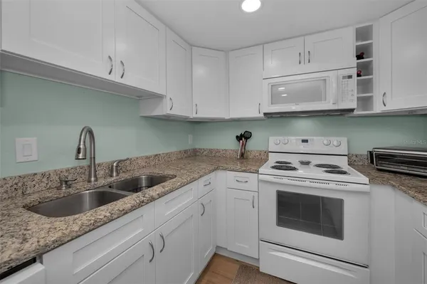 a kitchen with a white stove top oven and white cabinets