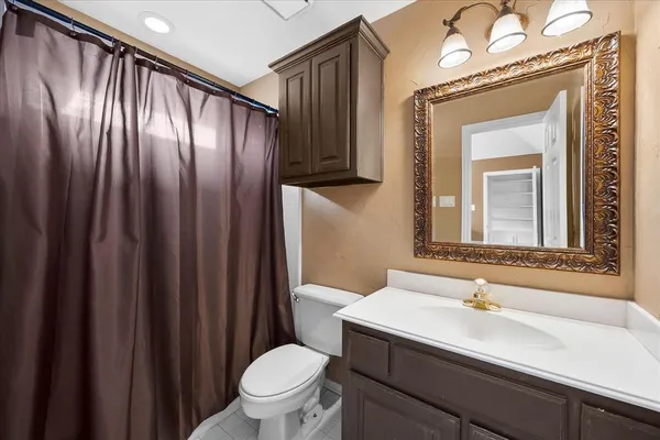 a bathroom with a sink a toilet a mirror and shower curtain