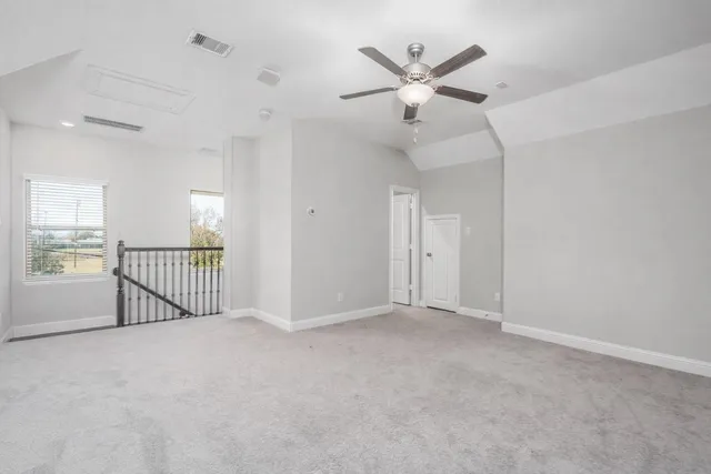 an empty room with chandelier fan and windows
