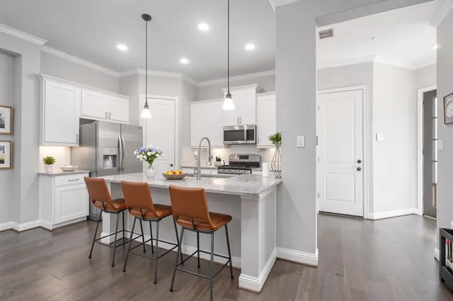 a kitchen with stainless steel appliances granite countertop a dining table chairs sink and wooden floor