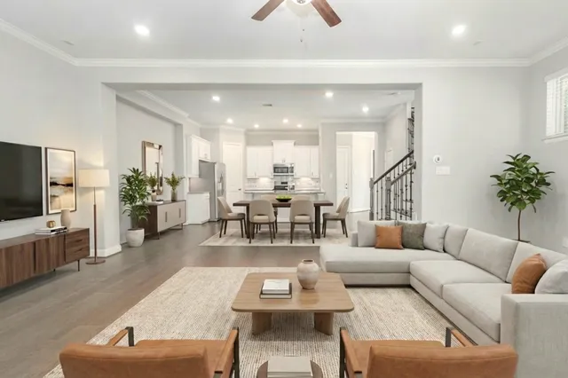 a living room with furniture kitchen view and a wooden floor