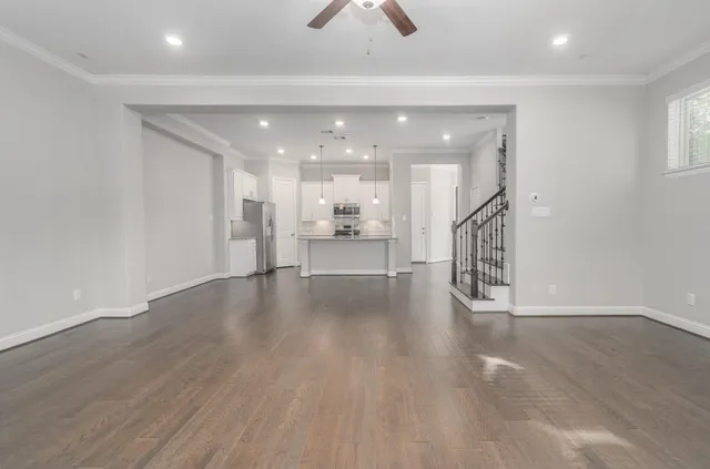 an empty room with wooden floor and a kitchen