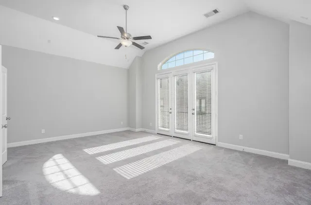 en empty room with windows and ceiling fan