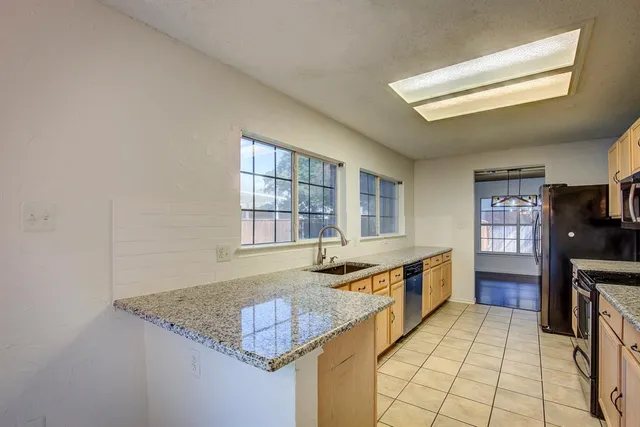 a kitchen with stainless steel appliances granite countertop a sink and a stove next to a window