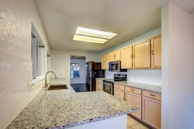 a kitchen with stainless steel appliances granite countertop sink stove refrigerator and cabinets
