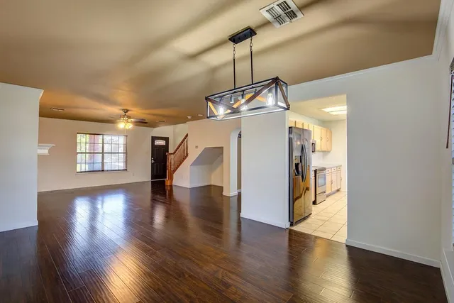 a view of a room with wooden floor ceiling fan and windows