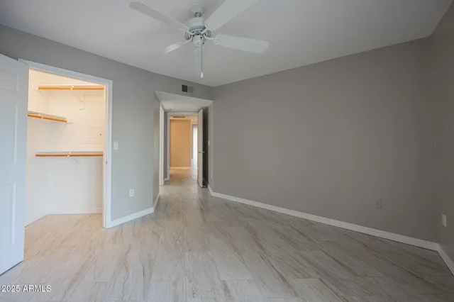 an empty room with wooden floor chandelier fan and windows