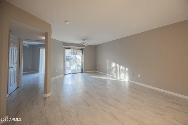 a view of empty room with wooden floor and fan