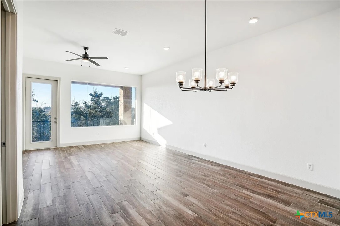289 Star Grass, Unit 3 Spring Branch, TX 78070 - Photo 12 of 40 an empty room with wooden floor ceiling fan and window