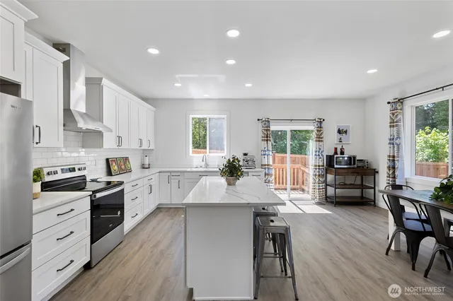 a large kitchen with kitchen island a large island a stove a dining table and chairs