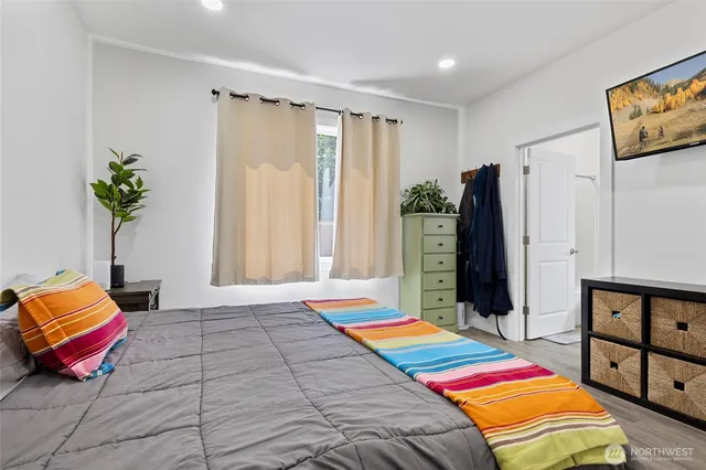 a bedroom with a bed a painting on the wall and a potted plant