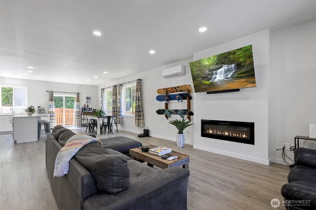 a living room with furniture a fireplace a flat screen tv and kitchen view