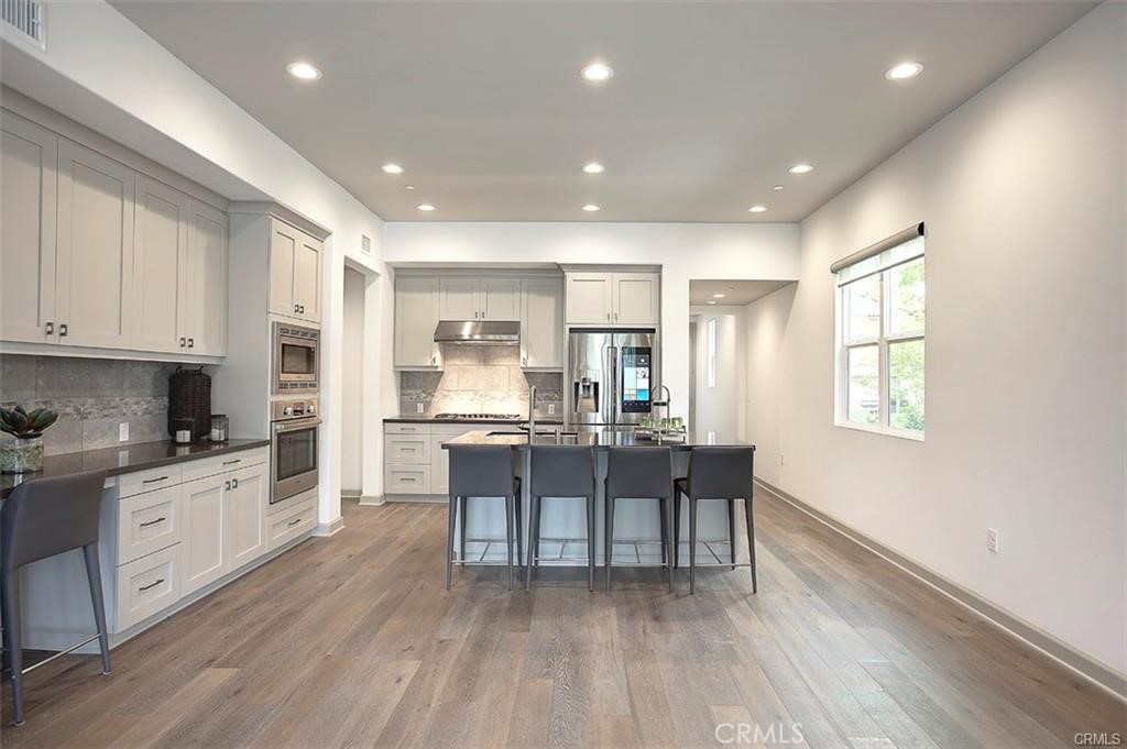 115 Fixie Irvine, CA 92618 - Photo 18 of 29 a kitchen with stainless steel appliances kitchen island granite countertop a stove a sink a refrigerator and white cabinets with wooden floor