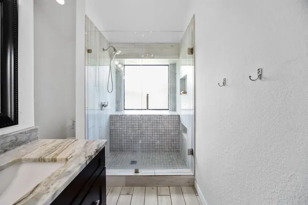 a bathroom with a granite countertop sink a mirror and shower