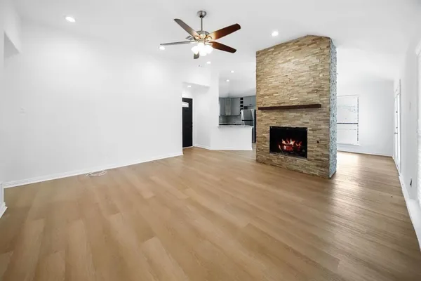 an empty room with wooden floor a fireplace and a ceiling fan