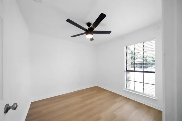 an empty room with a window and a ceiling fan