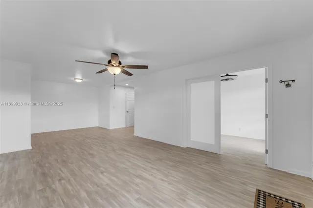 a view of empty room with wooden floor and ceiling fan