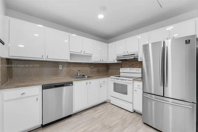 a kitchen with stainless steel appliances white cabinets and a refrigerator