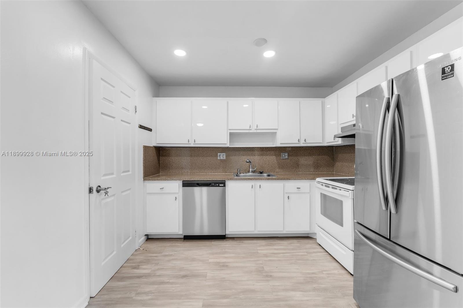 12820 Southwest 43rd Drive, Unit 233B Miami, FL 33175 - Photo 7 of 22 a kitchen with white cabinets and stainless steel appliances