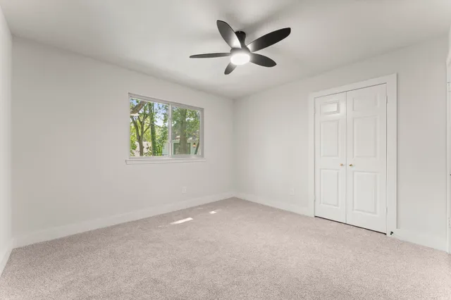 an empty room with window and ceiling fan