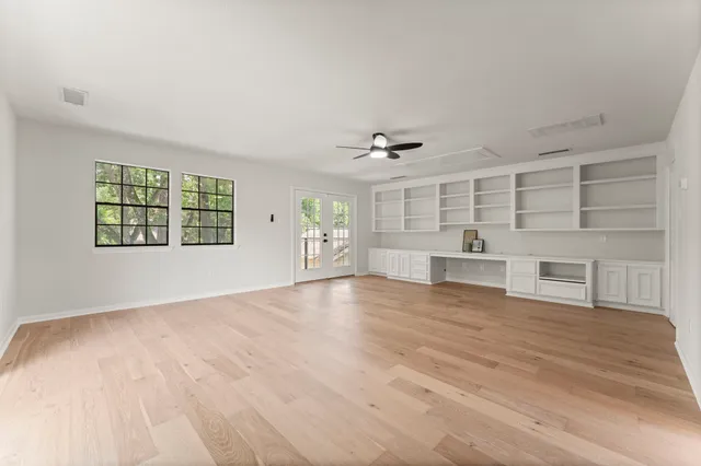 a view of an empty room with a window and wooden floor